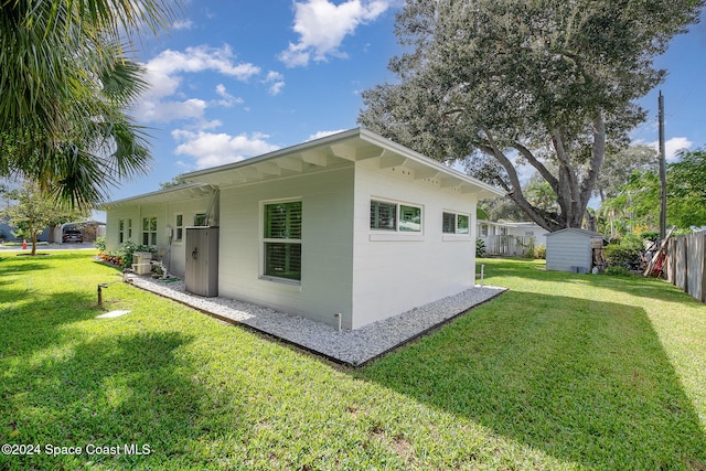 view of side of home with a storage shed and a lawn