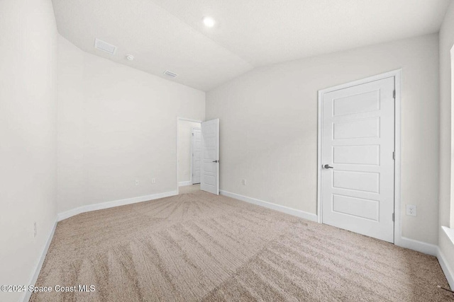 carpeted spare room with lofted ceiling