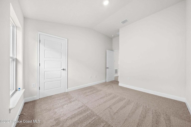 empty room with vaulted ceiling and carpet