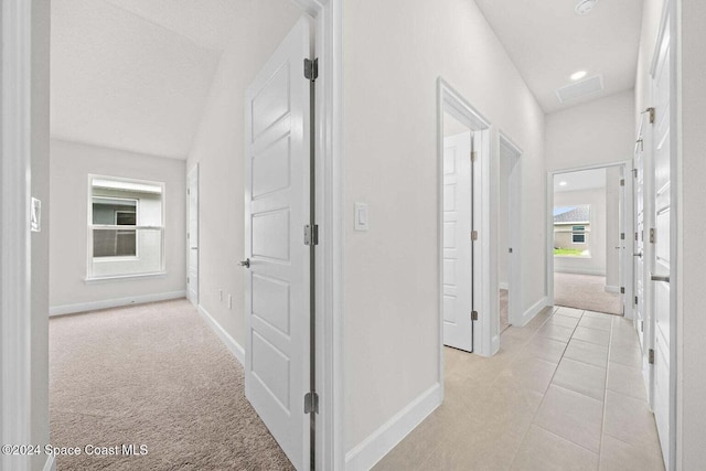 hall featuring light colored carpet and vaulted ceiling