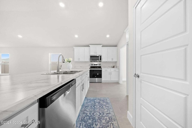 kitchen with stainless steel appliances, light tile patterned flooring, white cabinetry, sink, and light stone countertops