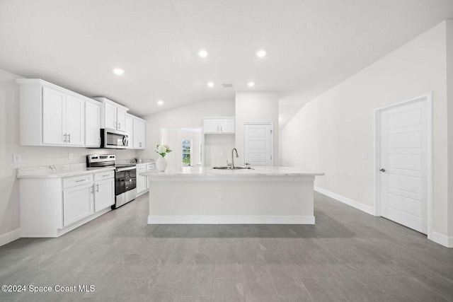 kitchen with vaulted ceiling, white cabinetry, a kitchen island with sink, and appliances with stainless steel finishes