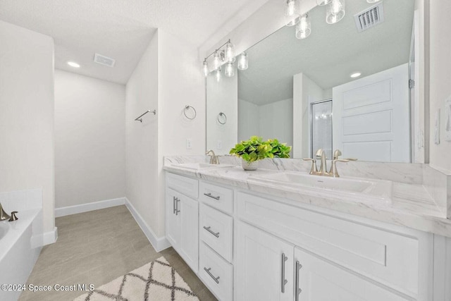 bathroom with vanity, shower with separate bathtub, and a textured ceiling