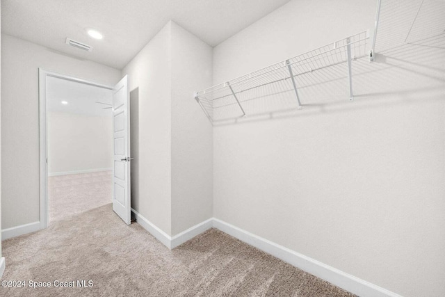 walk in closet featuring light colored carpet