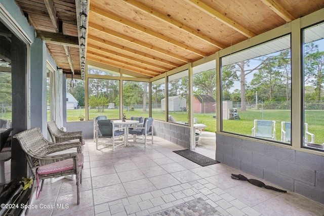 unfurnished sunroom featuring vaulted ceiling with beams, a healthy amount of sunlight, and wooden ceiling