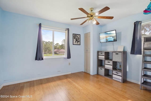 unfurnished office featuring ceiling fan, light hardwood / wood-style floors, and a healthy amount of sunlight