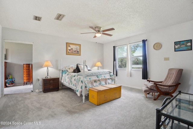 carpeted bedroom featuring ceiling fan and a textured ceiling