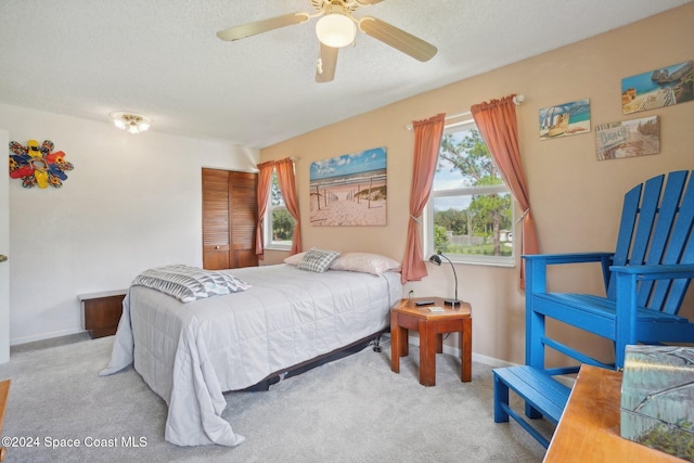 bedroom with ceiling fan, light colored carpet, a textured ceiling, and a closet