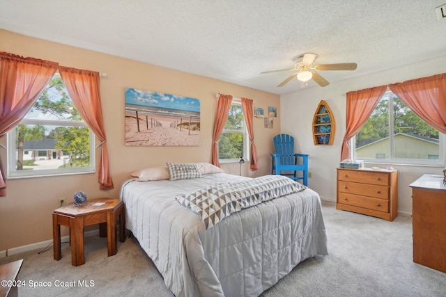 carpeted bedroom featuring multiple windows, a textured ceiling, and ceiling fan