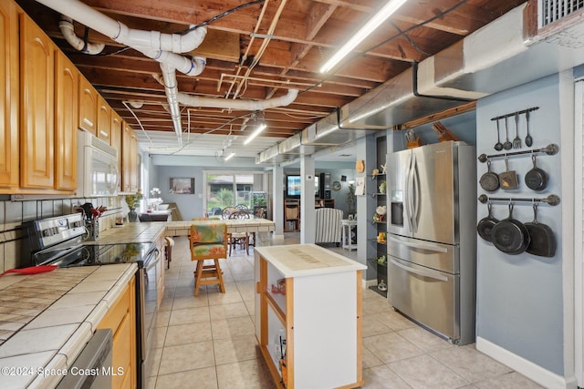 kitchen featuring stainless steel appliances, a kitchen island, tile counters, and light tile patterned flooring