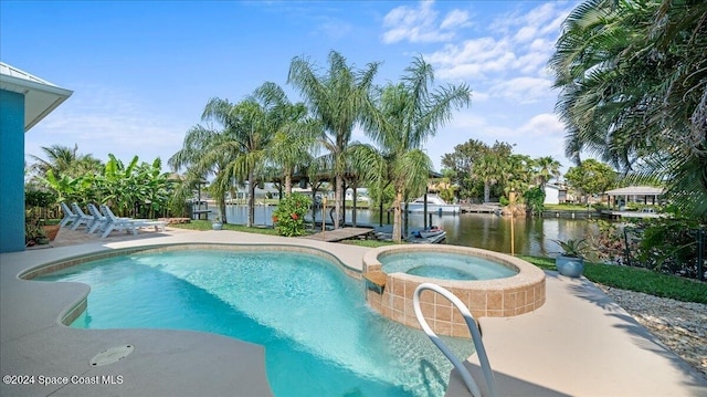 view of pool featuring an in ground hot tub, a water view, and a patio area