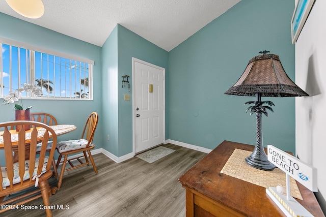 foyer entrance with a textured ceiling, wood finished floors, and baseboards