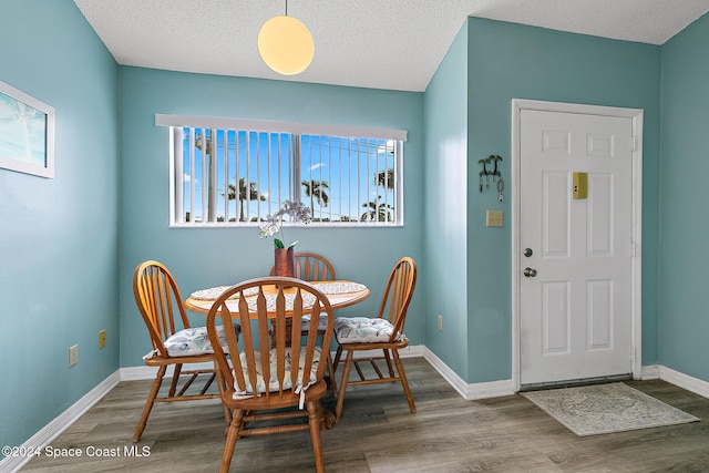 dining area featuring a textured ceiling, baseboards, and wood finished floors