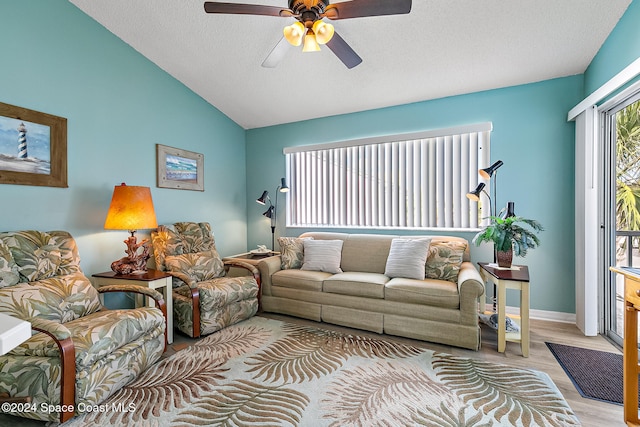 living area with a textured ceiling, a ceiling fan, baseboards, vaulted ceiling, and light wood-type flooring