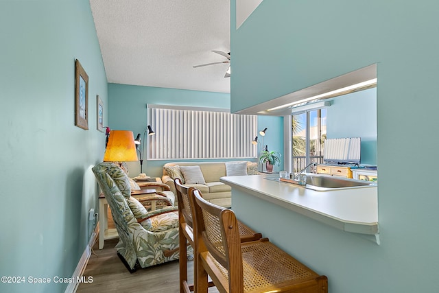 interior space with baseboards, a ceiling fan, wood finished floors, light countertops, and a textured ceiling