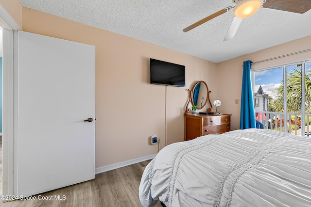 bedroom with a ceiling fan, light wood-type flooring, a textured ceiling, and baseboards