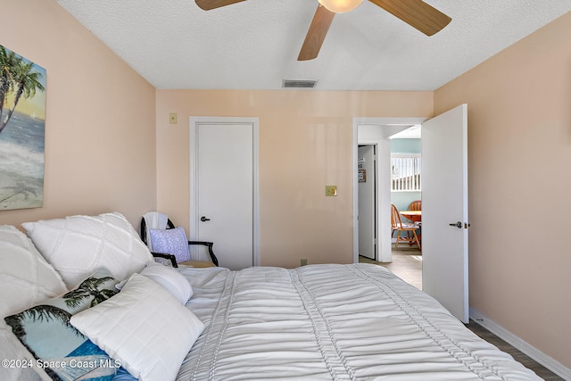 bedroom featuring baseboards, visible vents, ceiling fan, and a textured ceiling