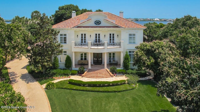 mediterranean / spanish-style house featuring a front yard, french doors, a water view, a balcony, and a patio