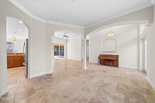 unfurnished living room featuring ornate columns, ceiling fan, sink, and ornamental molding