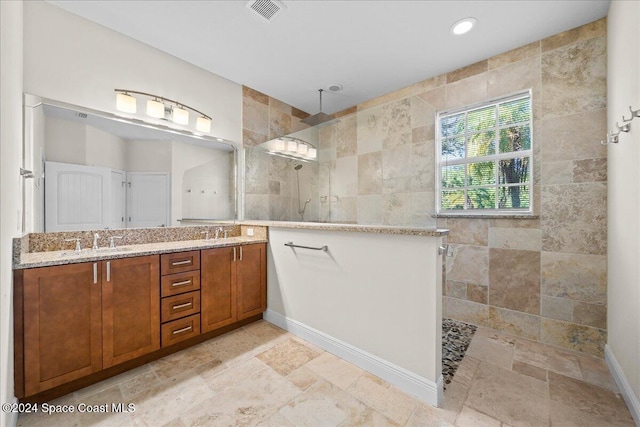 bathroom with tiled shower and vanity