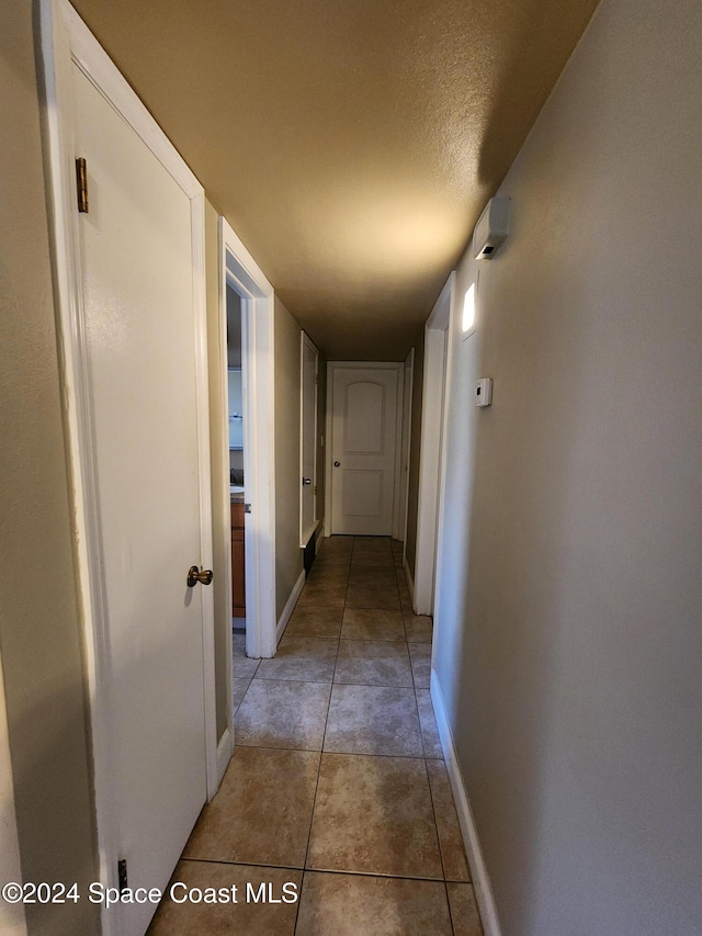 corridor with a textured ceiling and tile patterned floors