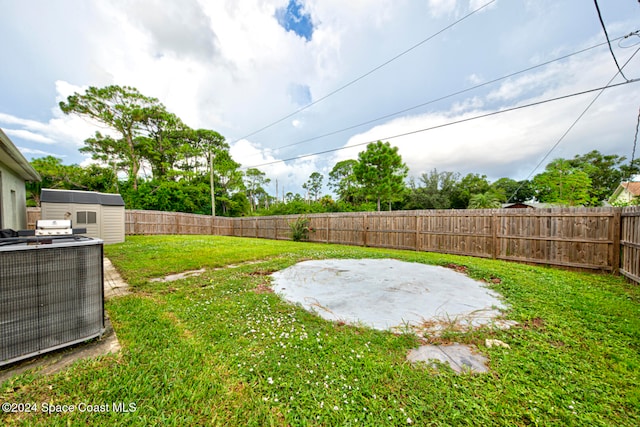 view of yard with central AC unit, a patio area, and a shed