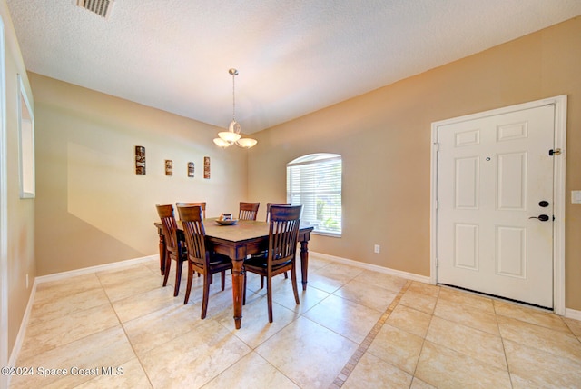 dining room with a textured ceiling, a notable chandelier, and light tile patterned floors