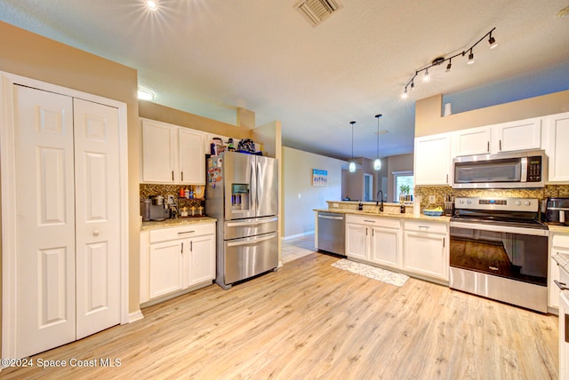 kitchen featuring white cabinetry, stainless steel appliances, hanging light fixtures, and light hardwood / wood-style flooring