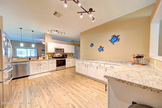 kitchen with stainless steel appliances, light hardwood / wood-style floors, kitchen peninsula, hanging light fixtures, and white cabinetry