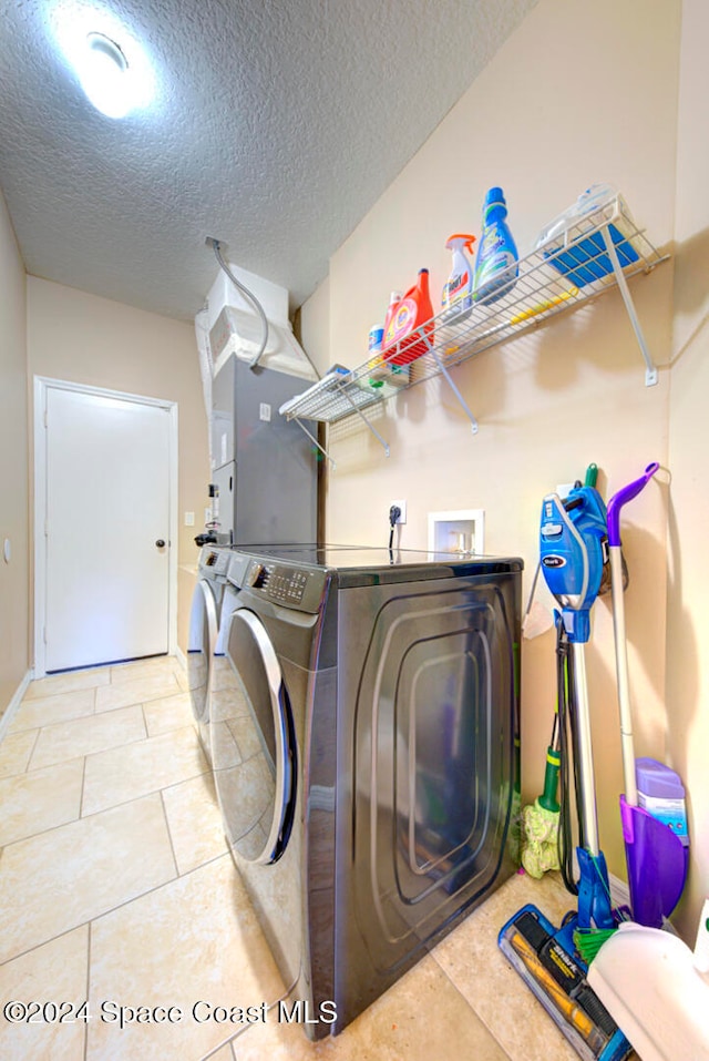 laundry room with tile patterned flooring, washing machine and dryer, and a textured ceiling