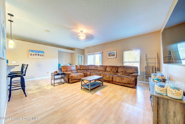 living room featuring ceiling fan, wood-type flooring, and a textured ceiling