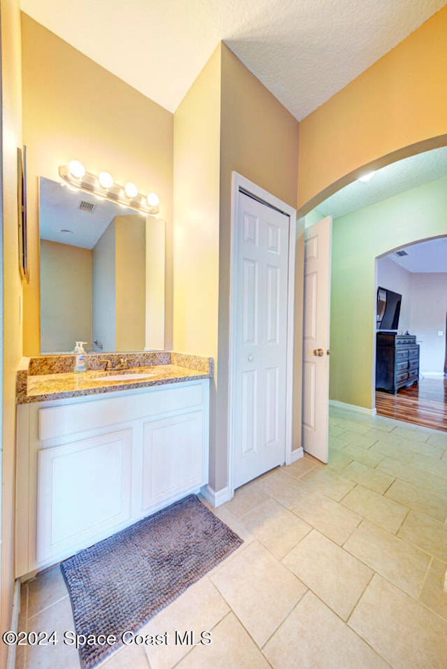 bathroom featuring tile patterned flooring, vanity, and a textured ceiling