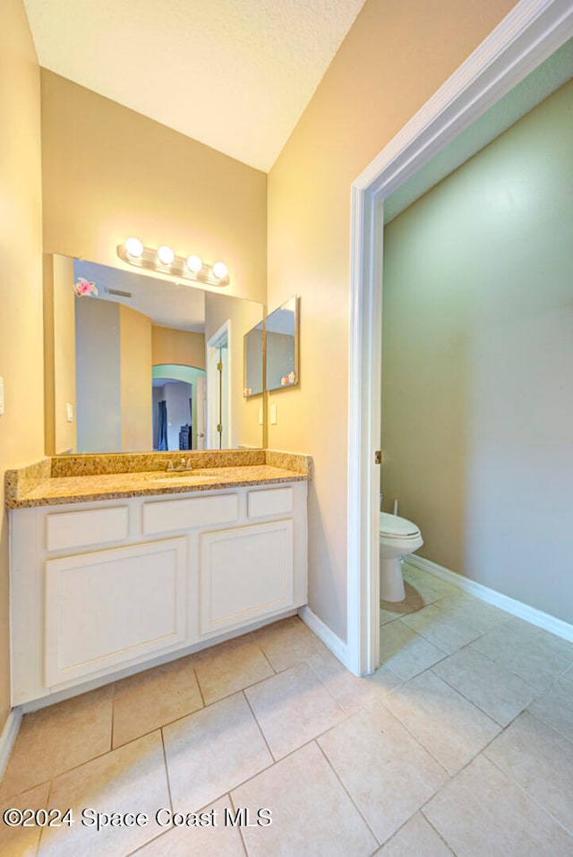 bathroom featuring vanity, tile patterned floors, toilet, and vaulted ceiling