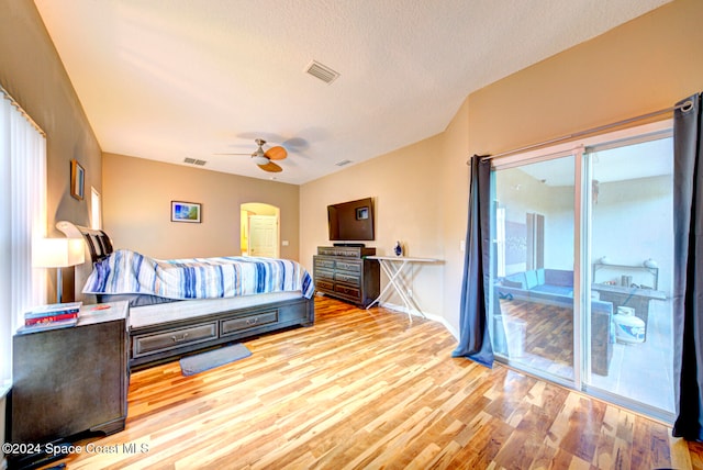 bedroom featuring access to outside, light wood-type flooring, a textured ceiling, and ceiling fan