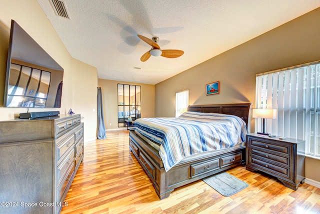 bedroom featuring light hardwood / wood-style floors, ceiling fan, and a textured ceiling