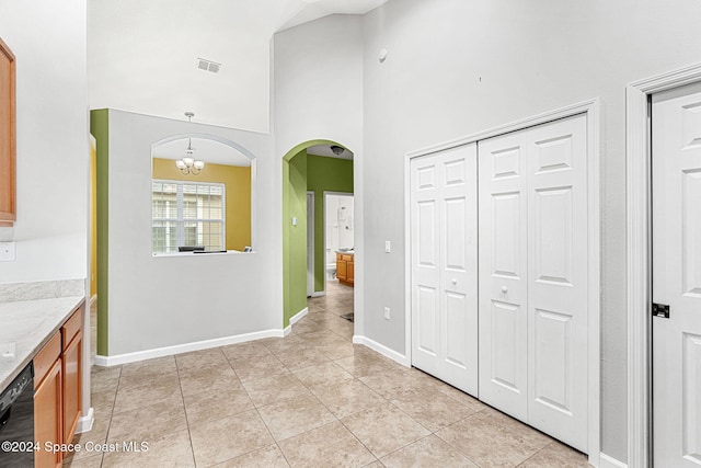 interior space featuring dishwasher, an inviting chandelier, hanging light fixtures, light tile patterned flooring, and light stone counters