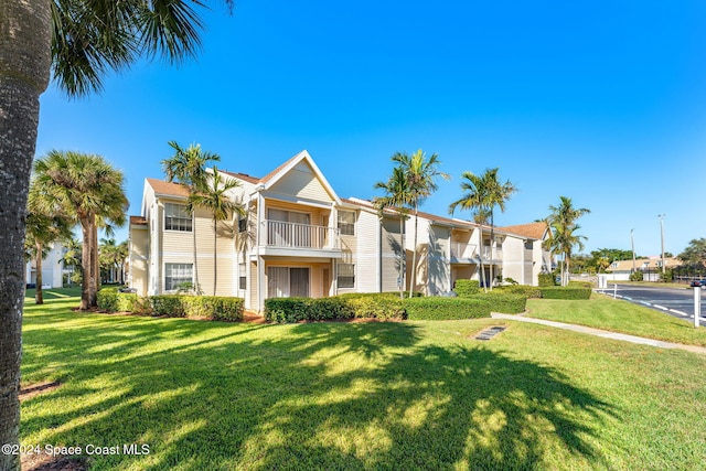 townhome / multi-family property featuring a balcony and a front yard