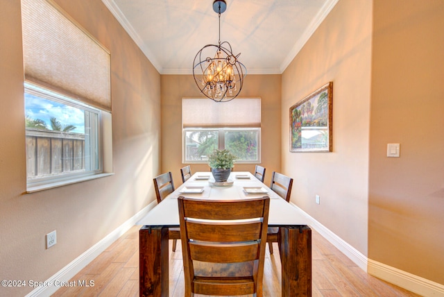 dining space with crown molding, a wealth of natural light, light hardwood / wood-style floors, and a chandelier