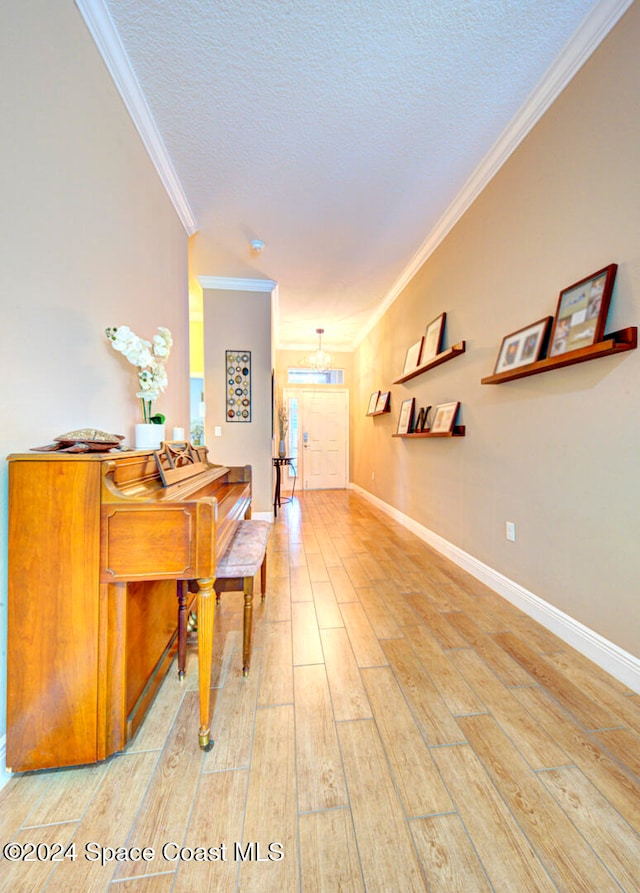 corridor featuring hardwood / wood-style flooring, crown molding, an inviting chandelier, and a textured ceiling