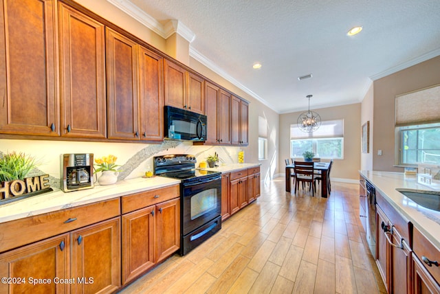 kitchen with hanging light fixtures, ornamental molding, light stone counters, black appliances, and light wood-type flooring