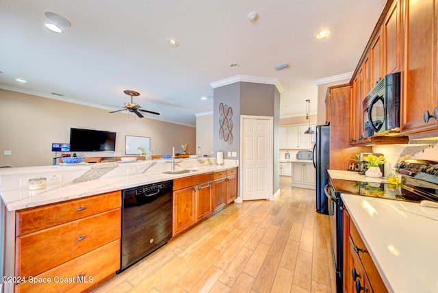 kitchen featuring sink, hanging light fixtures, light stone counters, black appliances, and light wood-type flooring