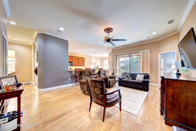 living room featuring crown molding, a textured ceiling, and light wood-type flooring