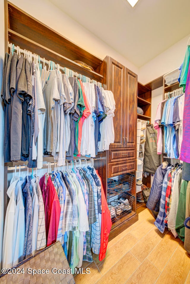 walk in closet with light hardwood / wood-style floors