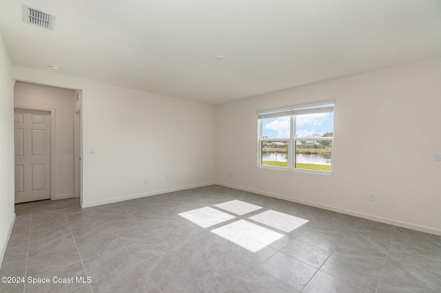 tiled empty room featuring a water view