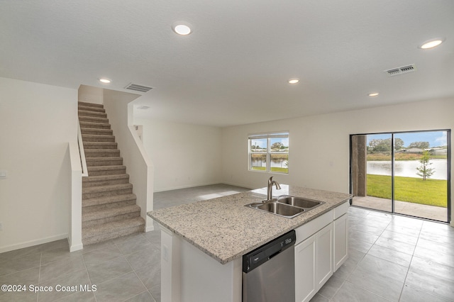 kitchen with white cabinets, a water view, sink, stainless steel dishwasher, and an island with sink