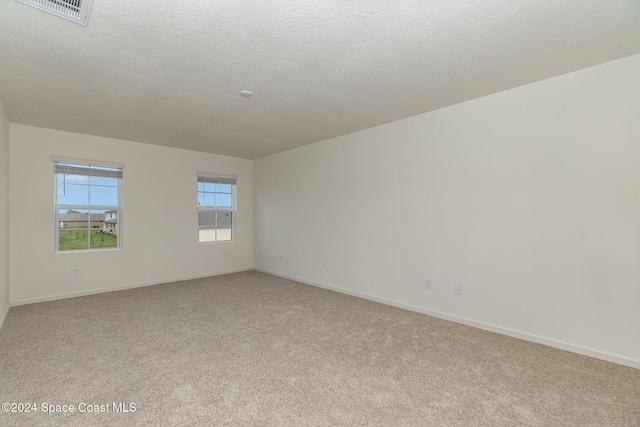 empty room featuring a textured ceiling and light carpet