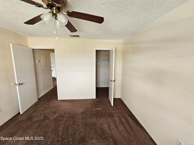 unfurnished bedroom featuring ceiling fan, a closet, a textured ceiling, and dark colored carpet