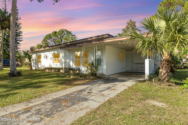 ranch-style house featuring a carport and a lawn