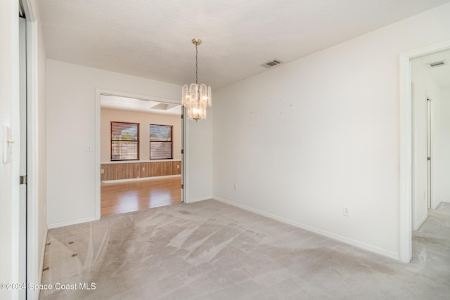 unfurnished dining area with a chandelier, a textured ceiling, and light colored carpet