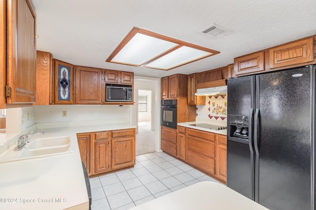 kitchen with sink, extractor fan, a textured ceiling, light tile patterned floors, and black appliances